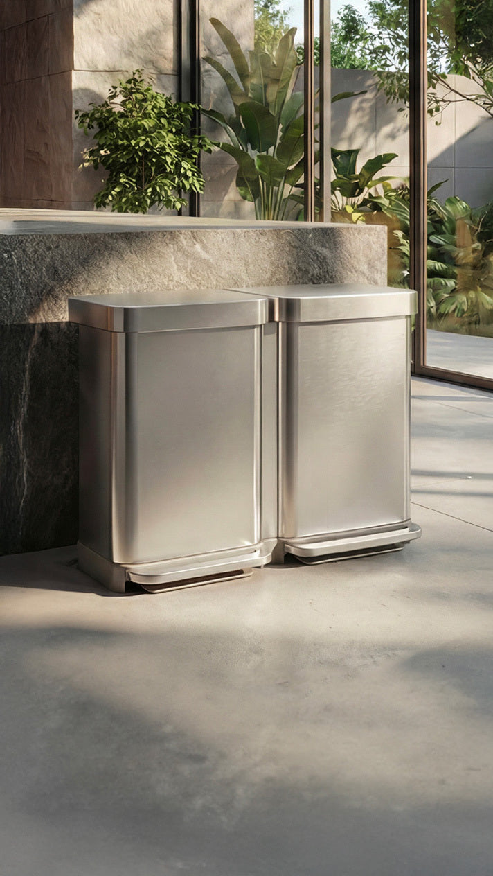 Simplehuman's 90L Step Recycler in Brushed in a modern kitchen setting with marble and wooden countertops with an outdoor patio with greenery. 