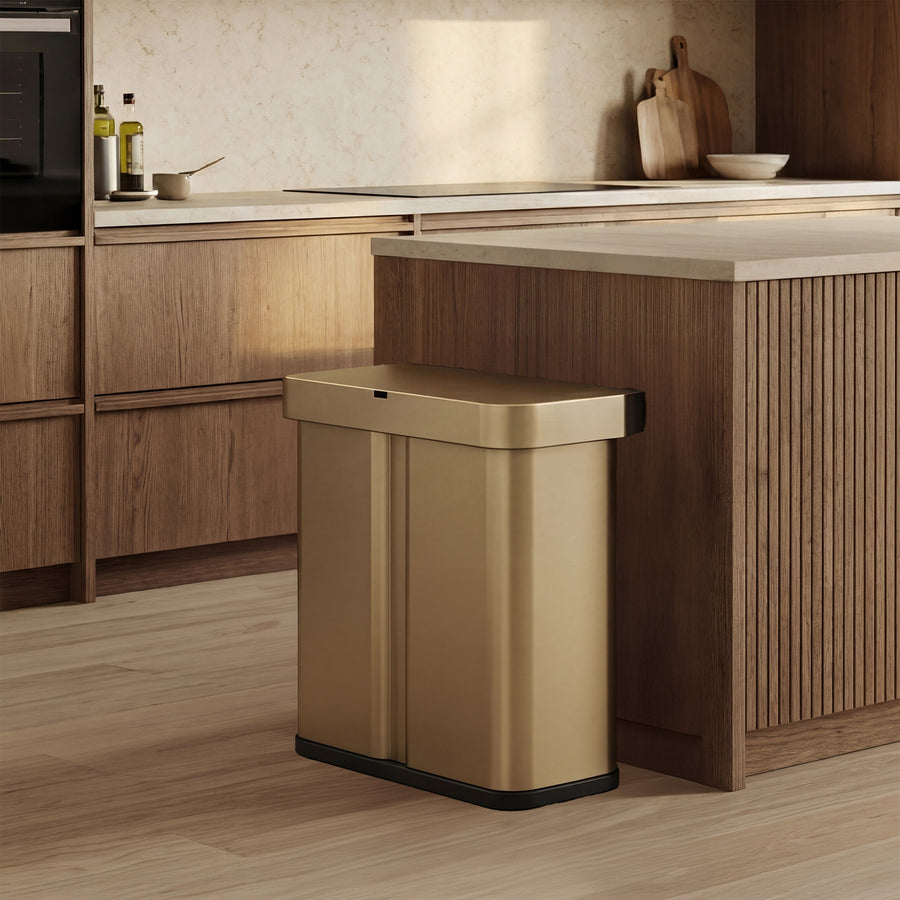 Simplehuman's Matte Gold Sensor Recycler featured in an elevated kitchen setting featured mainly with wood and marble.
