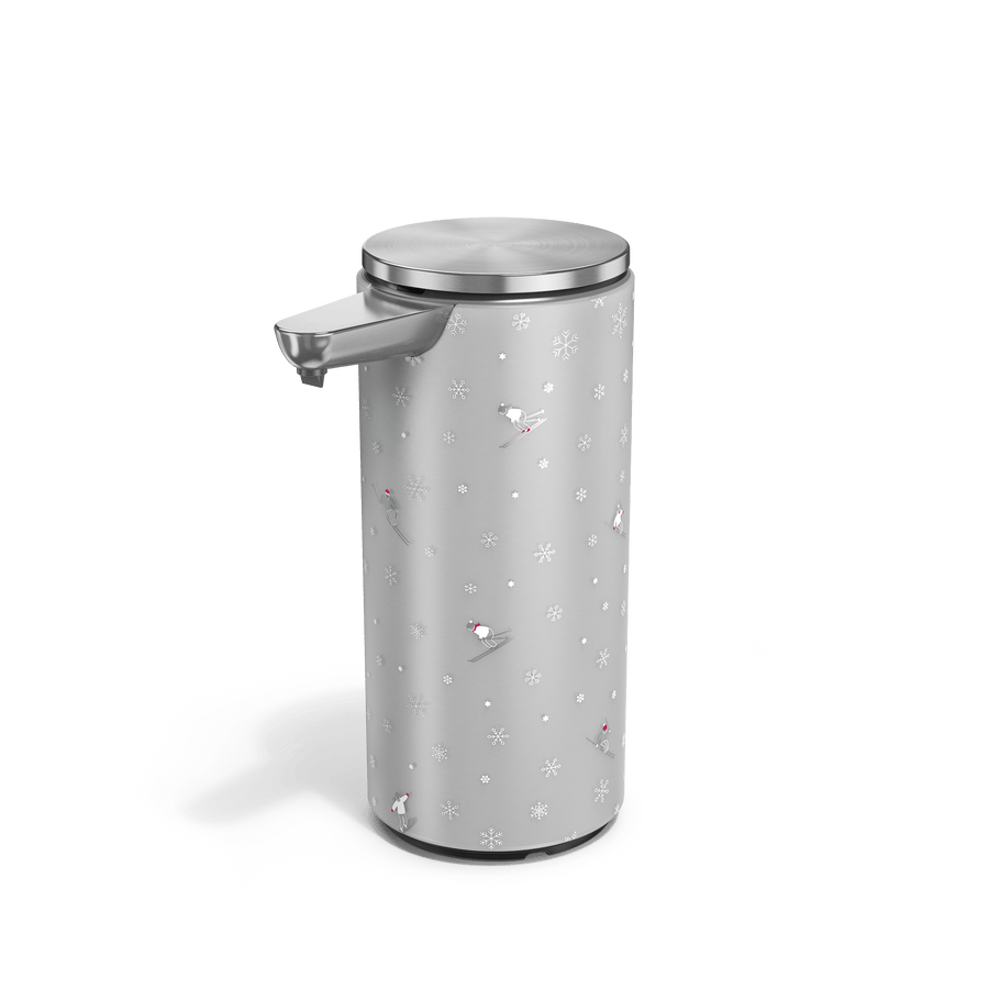 Angled view of Simplehuman Brushed 14 oz. Sensor Pump with holiday sleeve. White, frosted sleeve with skiers and snowflakes. 