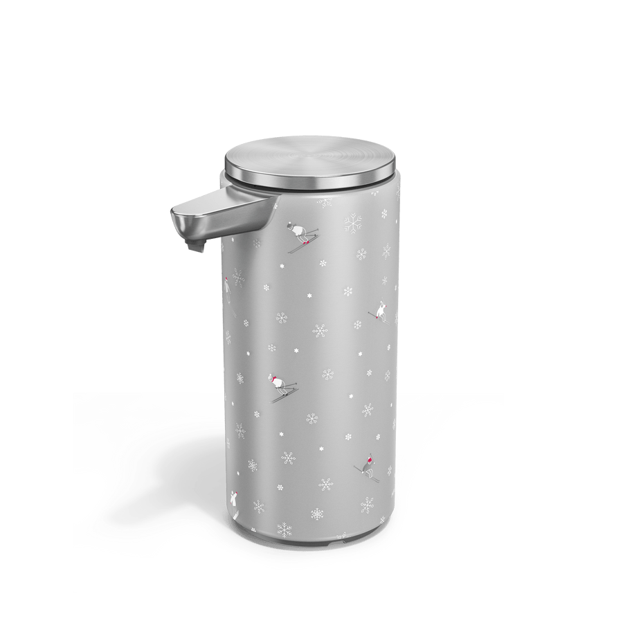 Angled view of Simplehuman Brushed 9 oz. Sensor Pump with holiday sleeve. White, frosted sleeve with skiers and snowflakes. 