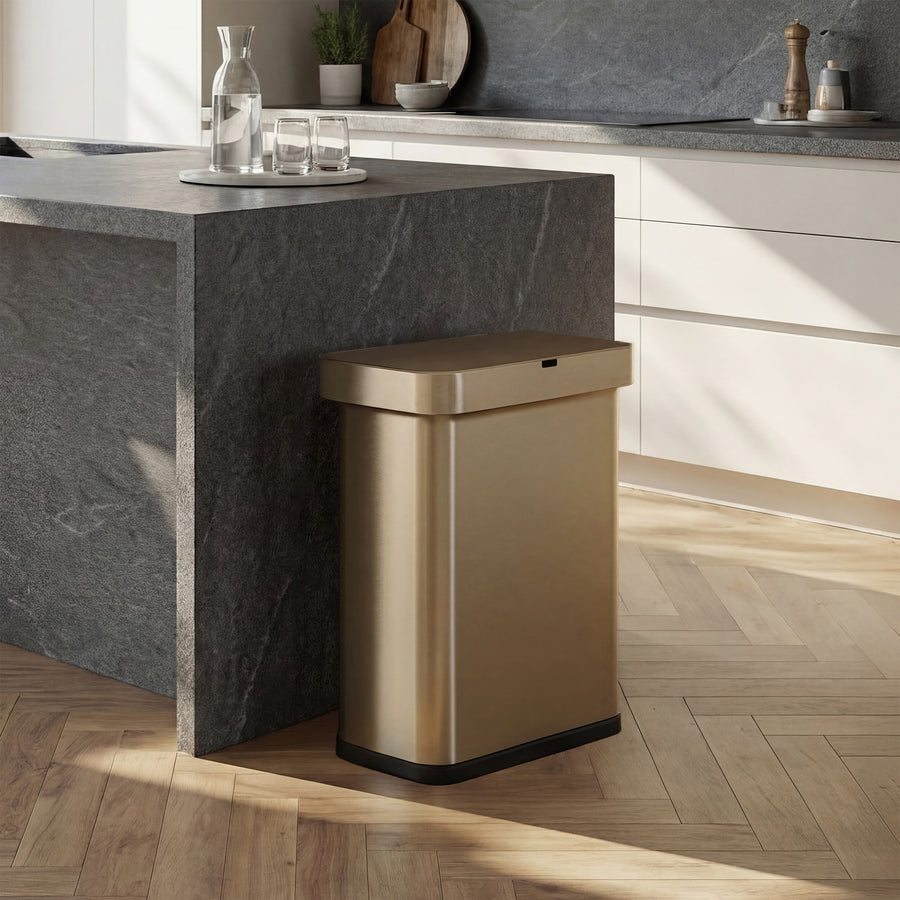Simplehuman's Matte Gold Sensor Can in an elevated kitchen with marble and white appliances with the back side facing a marble counter.