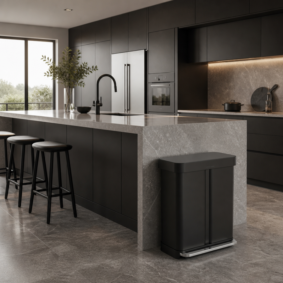 Simplehuman's 58L Step Can in Matte Black in a darker kitchen setting with a lot of natural lighting. 