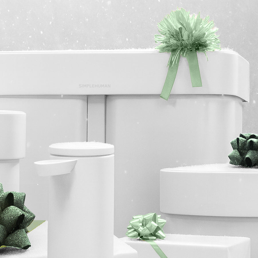 Explore the Simplehuman Holiday Gift Guide. This image features multiple flagship Simplehuman products in a white colorway wrapped with green bows with snow falling in the background.