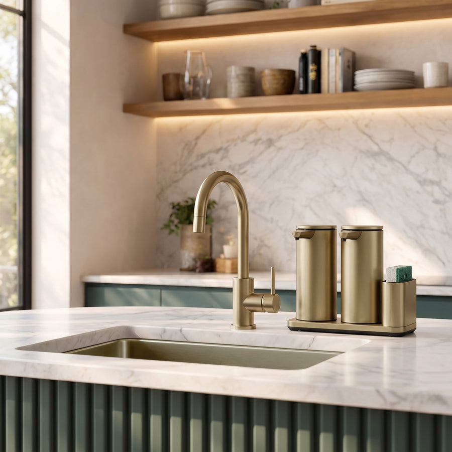 Simplehuman's Dual 14 oz. Sensor Pump in Matte Gold in a modern kitchen setting with marble counter top and green and wooden cabinets.