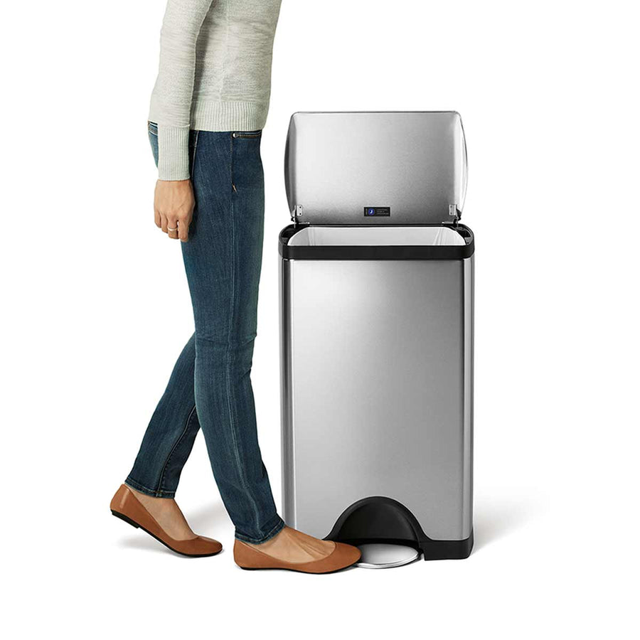 Simplehuman 38L Rectangular Step Can, Brushed Stainless Steel, with a person using the easy-access foot pedal.