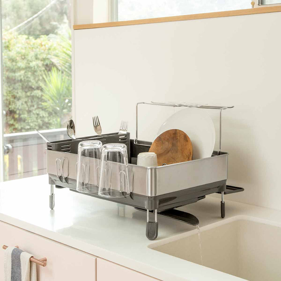 Simplehuman Brushed Stainless Steel Steel Frame Dishrack, elevated, with water draining via swivel spout into sink.