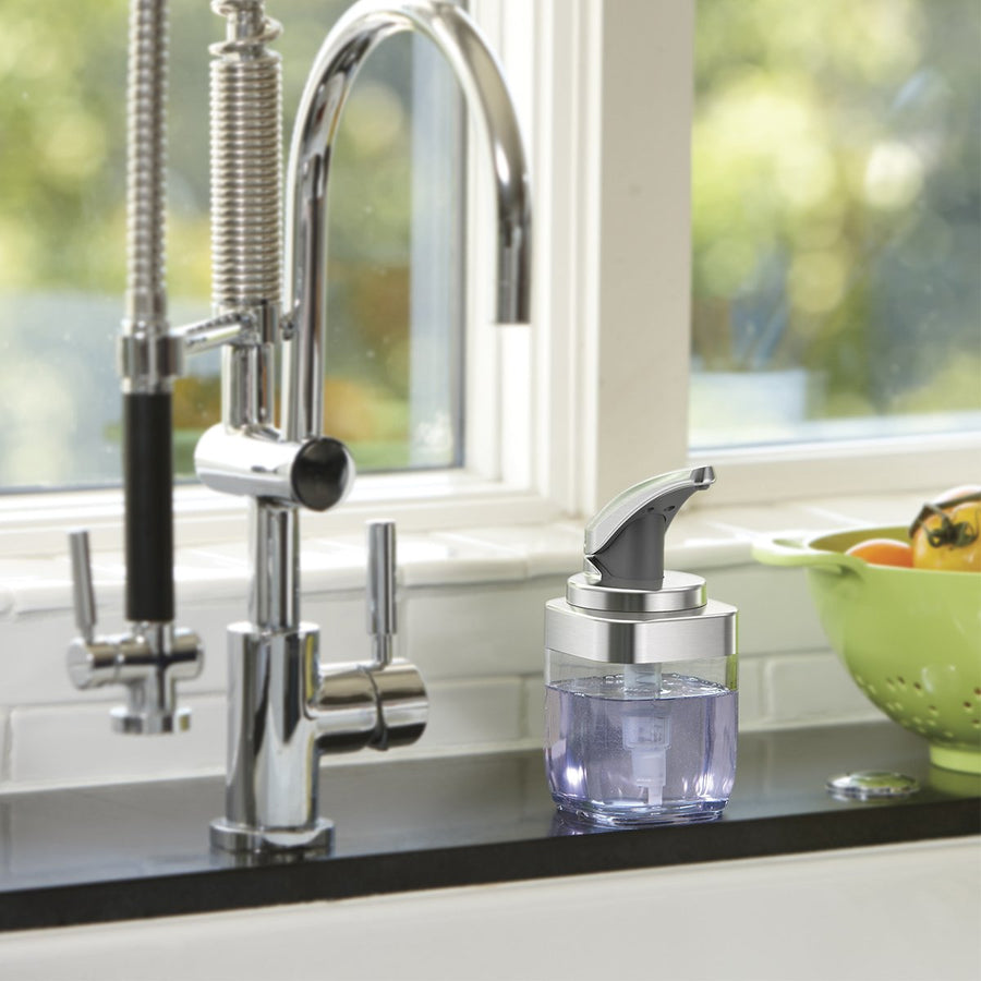 Simplehuman Square Push Pump in Brushed Nickel on a kitchen counter by a faucet, easy-view soap reservoir.
